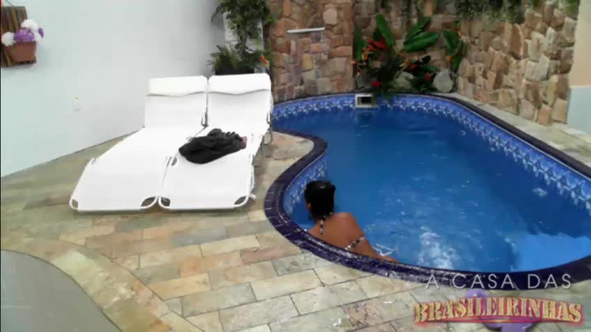 Dentro da piscina, a morena mete o consolo na buceta
